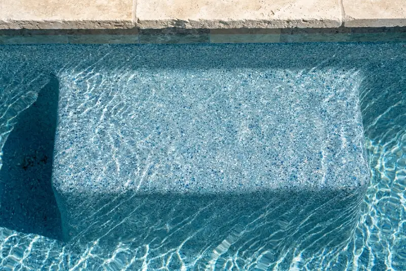 Close view of a blue quartz aggregate pool step under clear water